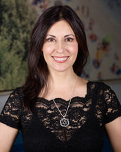 Load image into Gallery viewer, The image shows a woman with shoulder-length dark hair, smiling at the camera. She is wearing a black lace top with short sleeves and a Maelstrom Necklace. The background appears to be indoors, with a blurred wall that has some colorful elements, possibly decorations or artwork. The lighting is soft and even, highlighting her features and the details of her clothing and necklace.