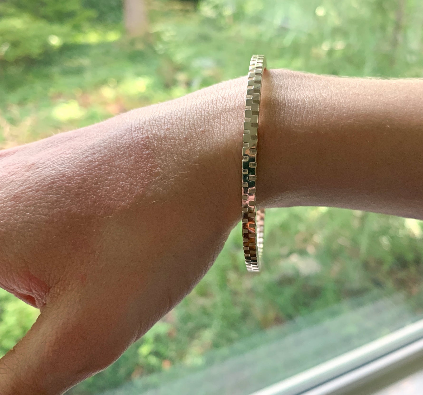 A closeup of the wrist of a model wearing our Check Bangle.