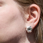 A closeup of the ear of a model wearing the Aperture Earrings