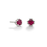 A pair of small silver studs on a white background. The gems at the center of each stud are a deep pink tourmaline. 