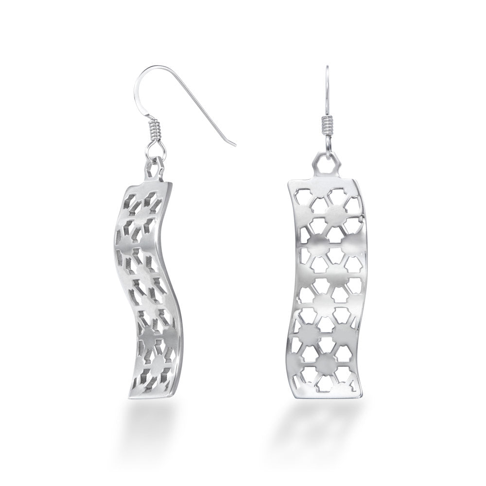 A pair of Hexwave Earrings hang in front of a white background. The sterling silver Hexwave earrings flow back and forth in a smooth wave design, cut with a hexagonal motif that breaks up the smooth lines, causing them to sparkle and shine at even the slightest motion. These hang down about 40mm each from Argentium hooks for tarnish resistance and added biocompatibility.
