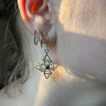 A closeup of a model's ear. One of the Pyrametry earrings hangs down from her earlobe. 