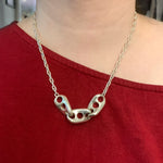 A model wearing the Seafarer Necklace over a red shirt. The image is a closeup of the necklace, and the model’s face is not visible. 