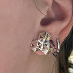 A picture of a model's ear as she's wearing the boardwalk earrings. The reflections in the center create an illusion of 6 windows when there are only 3. 