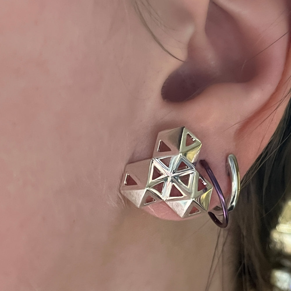 A picture of a model's ear as she's wearing the boardwalk earrings. The reflections in the center create an illusion of 6 windows when there are only 3. 