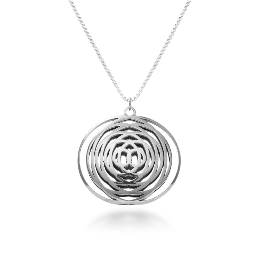 This is a phot of the Intererence Necklace, an ode to the rhythmic beauty of interference waves. Like ripples in a pool, the dual rings of silver radiate outward from the center, colliding and combining to form a mesmerising pendant. At just under 30mm wide and tall, and a full 10mm thick, this is beautifully large pendant to behold from any angle. Hanging from a beautiful 22 inch, 1.5mm box chain, this pendant is precision, beauty, and elegance all wrapped into one.