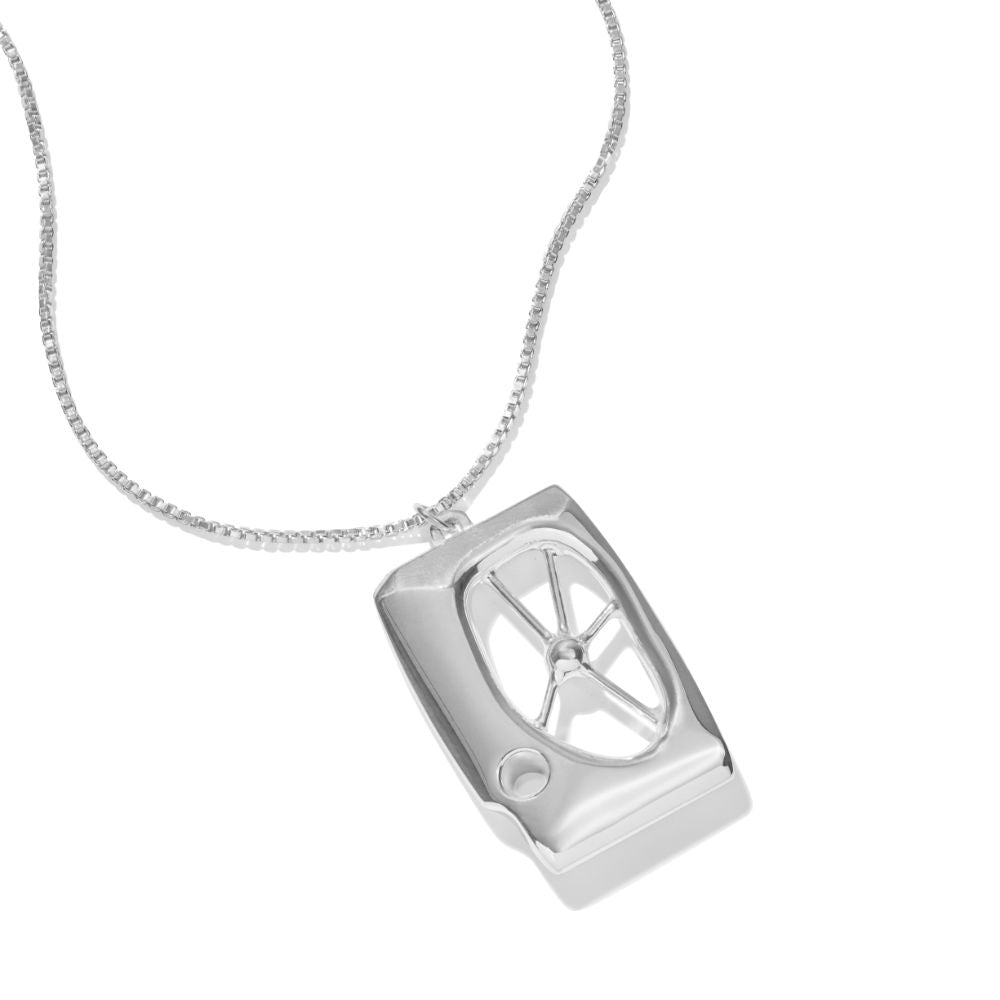 A photo of sterling silver Symbiosis Necklace, resting at a 45 degree angle on a white background. It is a pendant inspired in part by the works of Barbara Hepworth and Henry Moore, and in part by the adaptive world of biology. A not-quite-rectangular frame holds an off-center window, in the center of which is a solid sphere of silver, anchored to the walls with tendrils. A smaller hole cuts through the edge providing an unbalanced contrast. At the top, a bail hangs off center, but at the balance point for 
