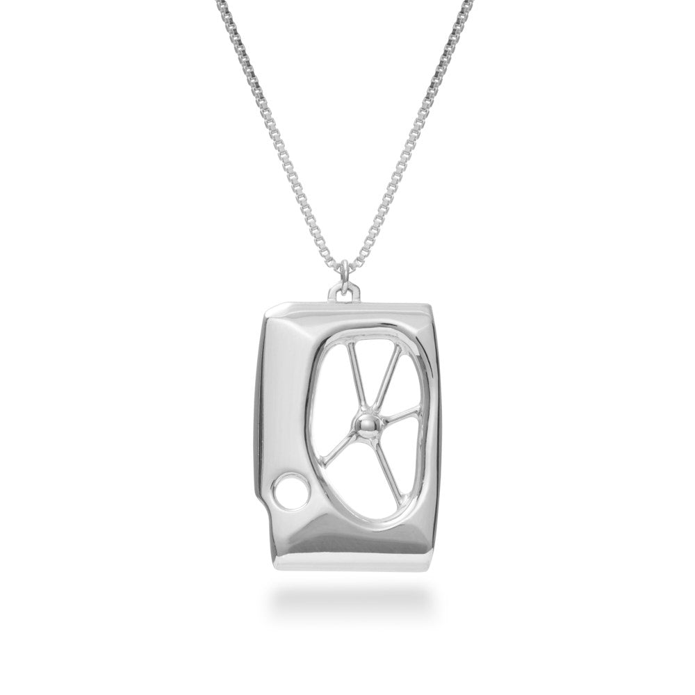 A photo of sterling silver Symbiosis Necklace, hanging against a white background. It is a pendant inspired in part by the works of Barbara Hepworth and Henry Moore, and in part by the adaptive world of biology. A not-quite-rectangular frame holds an off-center window, in the center of which is a solid sphere of silver, anchored to the walls with tendrils. A smaller hole cuts through the edge providing an unbalanced contrast. At the top, a bail hangs off center, but at the balance point for the piece. 