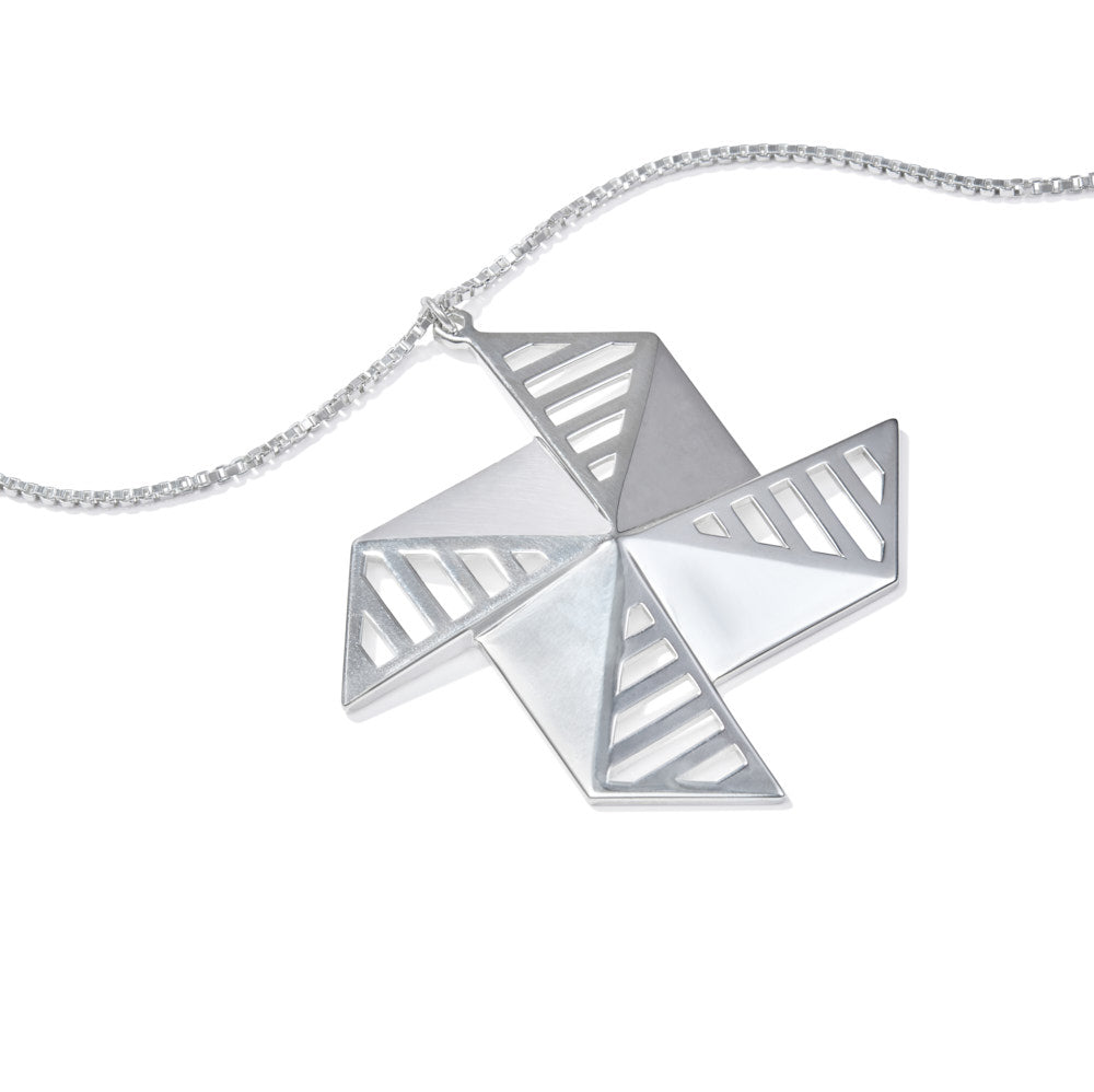 An image of the sterling sliver Windmolen Necklace lying on a white background at a 45 degree angle. The necklace has a unique windmill-inspired design, almost like a pinwheel of silver on a chain. It's a large piece at 60mm wide, but it's been designed to be a mere 23 grams in weight. The angles ensure this piece stays perfectly rigid, with comfortable corners despite its almost shuriken-like appearance. Like all of our pieces, this is meant to last a lifetime. A piece of which you can be truly proud.