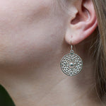 An image of a model wearing the Atom Earrings. This is a closeup of the model's ear taken from the left side, showing the atom earring in detail. 