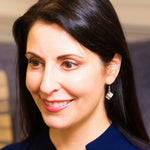 A brunette model wears our sterling silver Tesseract Earrings. This shows a headshot with the earring in her left ear. 