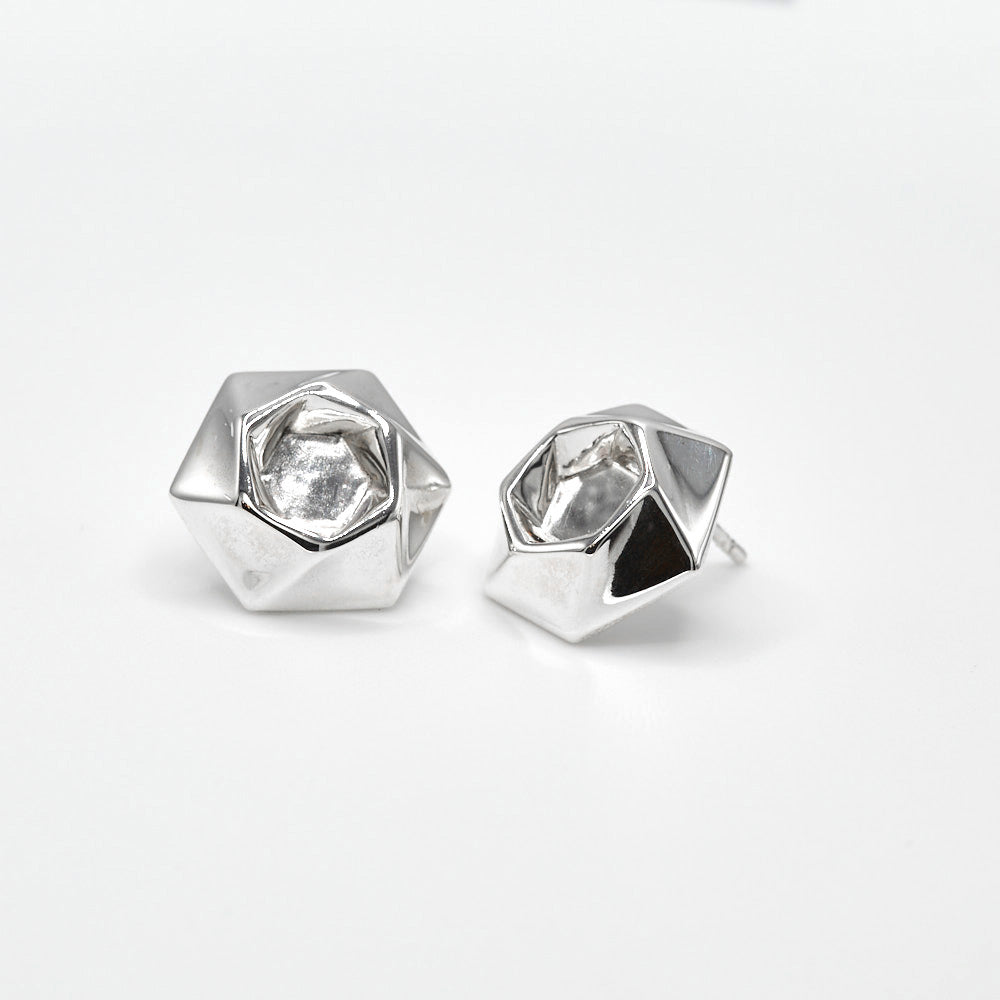 A pair of sterling silver Aperture Earrings against a white surface. The earrings feature a twisty hexagonal design, and measure about 15.7mm from flat to flat. At 7 grams each, they're eminently comfortable to wear, but still make a bold statement. 