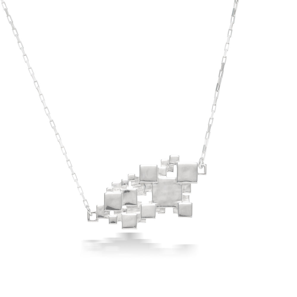 A product photo of our Sea of Squares Necklace hanging in front of a white background. The necklace pendant is an abstract collection of squares at varying heights, and the pendant sits inline along a rectangular link chain. The chain attaches at two different heights on the sides.  