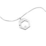 A sterling silver Hextech Necklace lies at an angle on a white surface. The futuristic, sterling silver HexTech Necklace features an array of hexagons at varying levels, hanging on a hexagonal bail from a 22" 1mm Italian made box chain. The recesses are depolished to give a variety of textures in the piece.