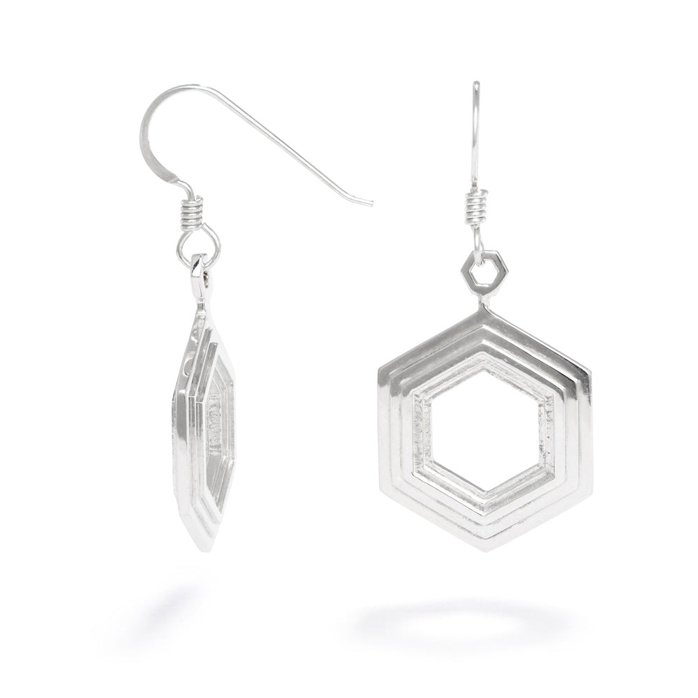 A pair of Stepped Hexagon Earrings hang against a white background. These sterling silver earrings have a modern geometric design featuring rising and falling levels of hexagons. They're 19mm wide and 3mm thick and part of our Stepped Hexagon collection.