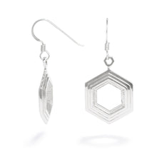 Load image into Gallery viewer, A pair of Stepped Hexagon Earrings hang against a white background. These sterling silver earrings have a modern geometric design featuring rising and falling levels of hexagons. They&#39;re 19mm wide and 3mm thick and part of our Stepped Hexagon collection.
