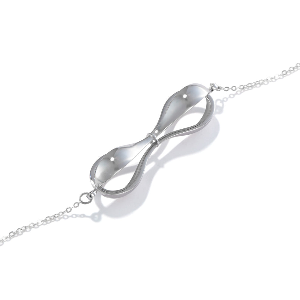A photo of our sterling silver Tri-Curve Necklace lying on a white table at a 45 degree angle. The necklace is a combination of three thick silver curves, joined together at the ends and at the center. There are spaces matching the curve shape in between each curve. It hangs inline on a cable necklace. 