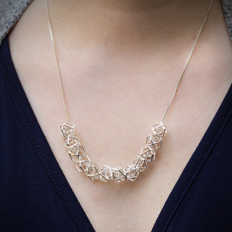A closeup photo of our Hexagonal Ice Crystal Necklace around the neck of a model. 
