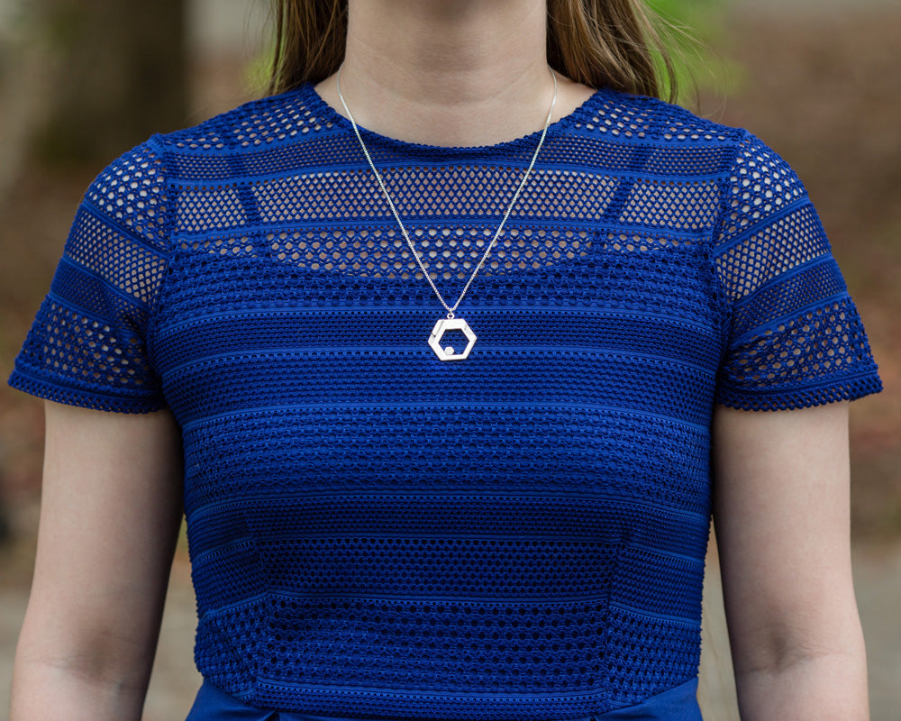 A model in a blue lace-top shirt wears a Hextech Necklace. The model's face is not visible. 