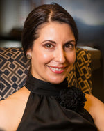 A photo of a smiling brunette model wearing our Hexagonal Pyramid Stud Earrings. The model is wearing a black dress and is looking toward the camera. 